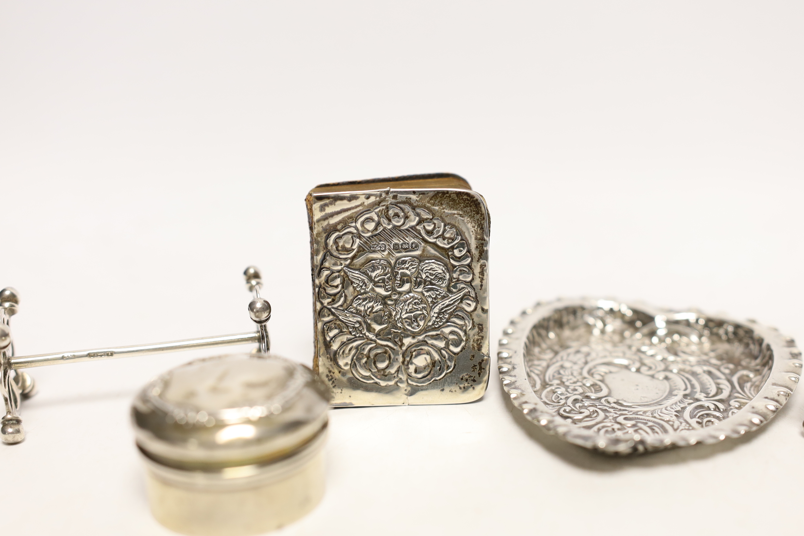 An Edwardian repousse silver mounted small bible, a silver circular pill box, a pair of silver salts, silver pepperette, pair of silver knife rests and a heart shaped dish.